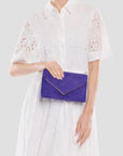 Person holding a purple clutch against a white background