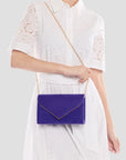 Person wearing a white lace outfit with a blue handbag on a light gray background