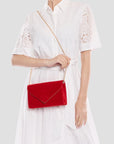 Person wearing a white dress holding a red handbag against a light gray background
