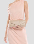 Woman in a pink dress holding a gold clutch against a white background
