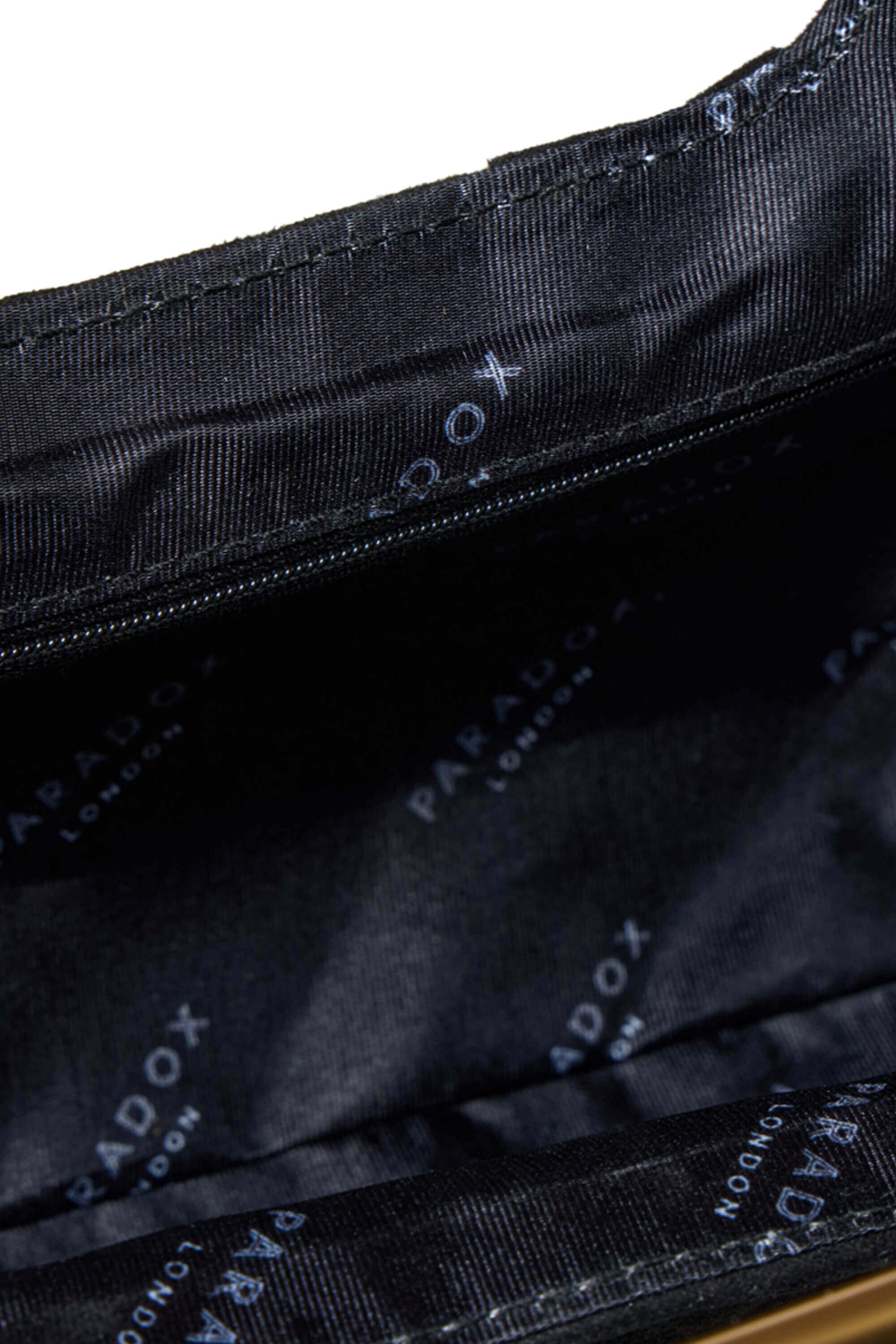 Close-up of the interior lining of a black bag, showing a zipper and a repeating light blue 'PARADOX LONDON' logo print on the fabric.